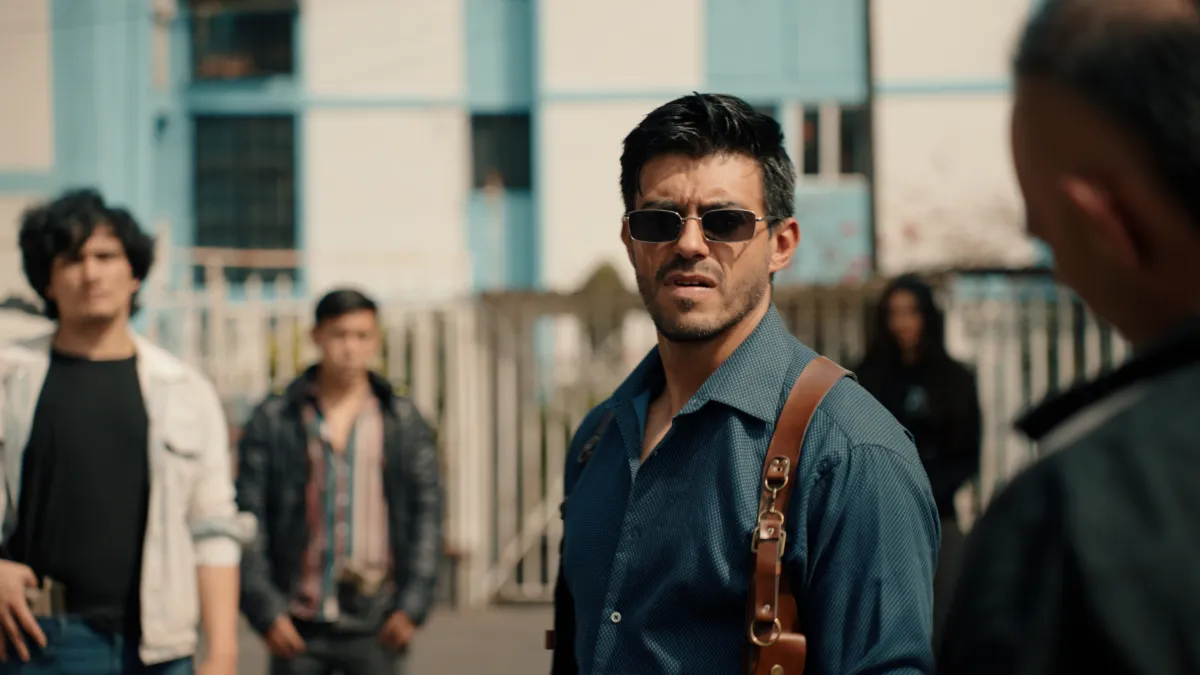 Still from La Maleta: a man in sunglasses facing a group in a street in Mexico